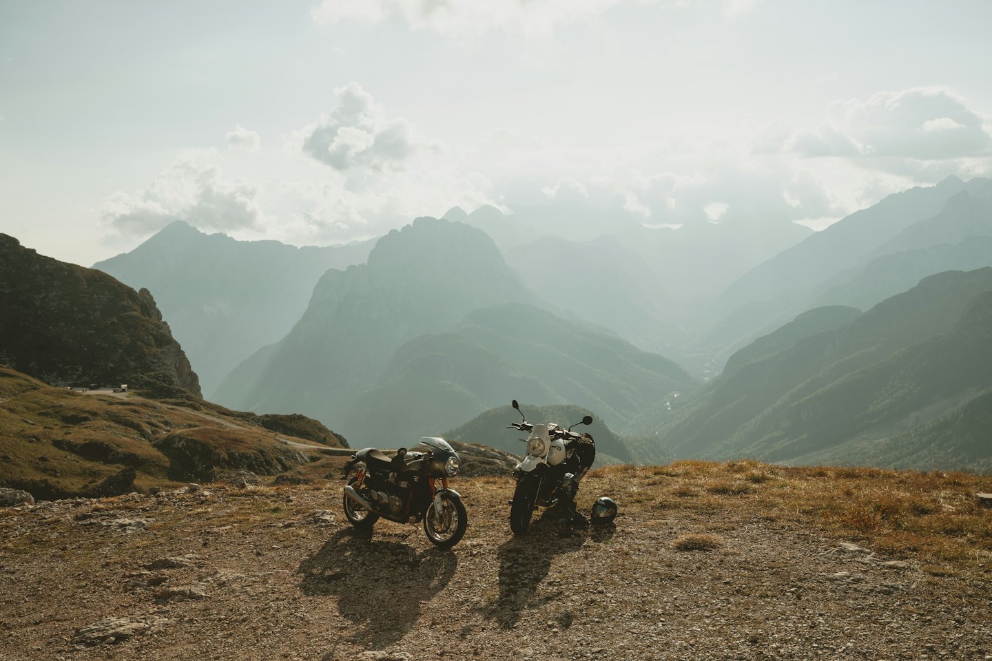 Two motorcycles parked on a plateau overlooking a mountain valley.